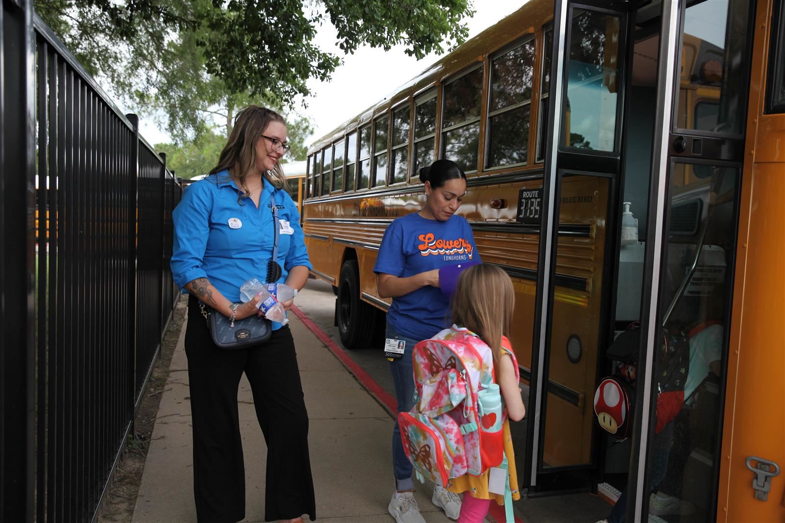 Annie Morris with Outback Steakhouse assists Lowery Elementary School Aide Wanda Orellana in welcoming young bus riders.